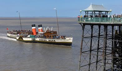 A full paddle steaming coming in to dock by a pier