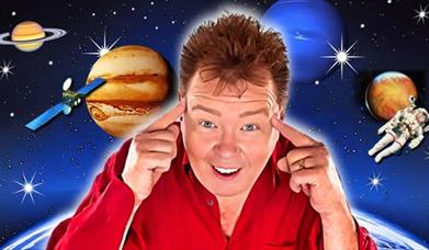 Mugshot of comedian Andy Ford wearing a red shirt and pointing to his ears