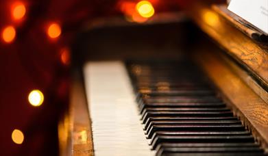 A piano keyboard with a bokeh of Christmas lights in the background