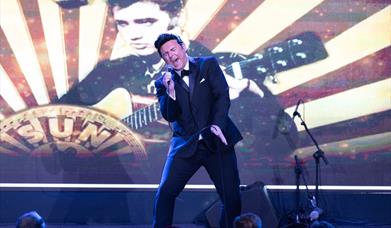 An Elvis impersonator signing on stage