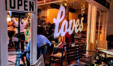 Looking from outside at night through a window into the Weston-super-Mare music and cafe bar Loves