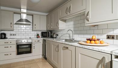 A modern kitchen with white units and tiles in a self catering cottage at Webbington Farm, near Weston-super-Mare