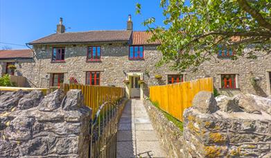 Exterior image of a fenced path leading towards the stone buildings of Norton Court Farm self-catering holiday cottages near Weston-super-Mare