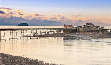 A view of Weston-super-Mare's Birnbeck Pier at sunset with the island of Steep Holm in the background