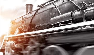 A blurred black, white and sepia image of the front of a steam train travelling at speed