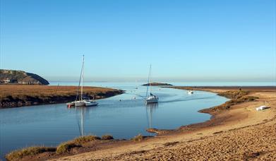 Uphill Beach and estuary near Weston-super-Mare. The image shows the sandy beach, boats in the estuary and a small island at the mouth of the estuary