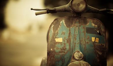 Front view of a rusty green Vespa-style scooter