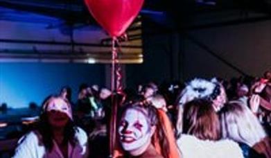 People in Halloween costumes partying and holding a red balloon