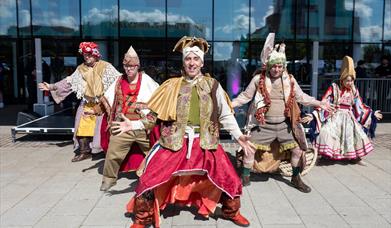A group of five dancers in Cossack-style costumes