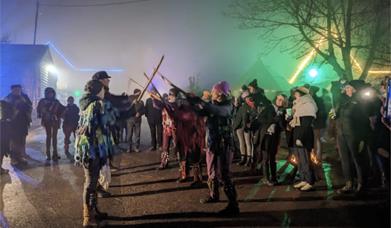 Image of a wassail festival with people creating an arch from sticks