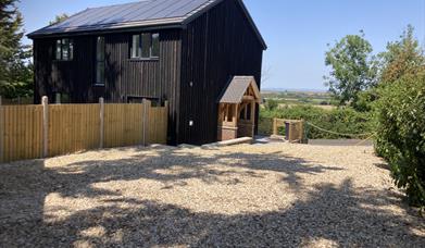 Outside view of a black wooden house and a shingle drive