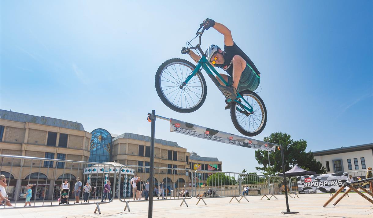 Mountain Bike Stunt Rider Rich Pearson jumps over a high bar challenge in the Italian Gardens Weston-super-Mare