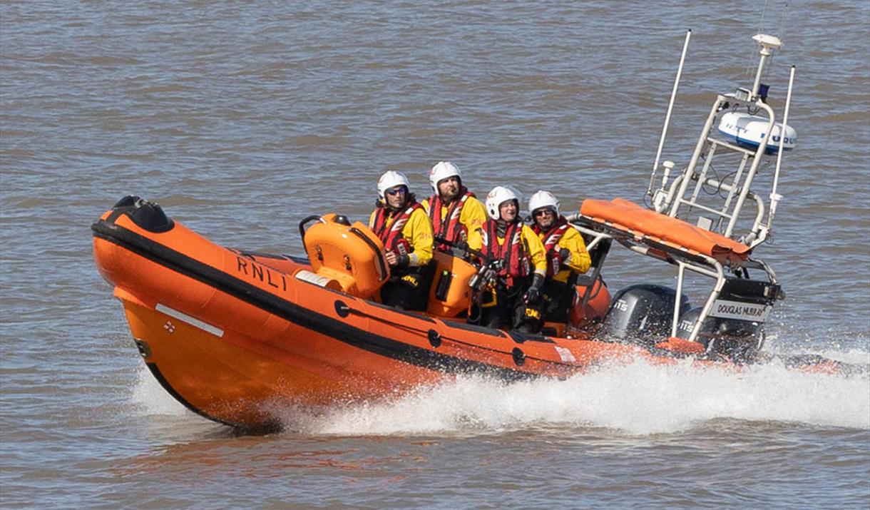 Four members of the RNLI on board an inflatable lifeboat
