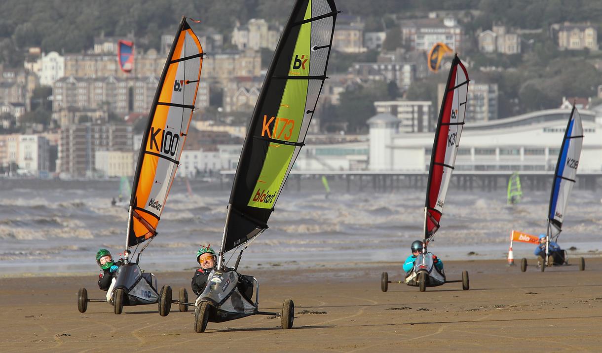 Four land yachts racing across a beach