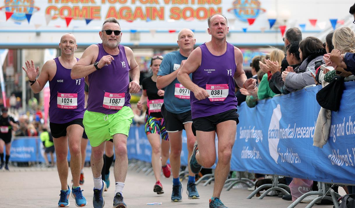 A group of runners being cheered by the crowd