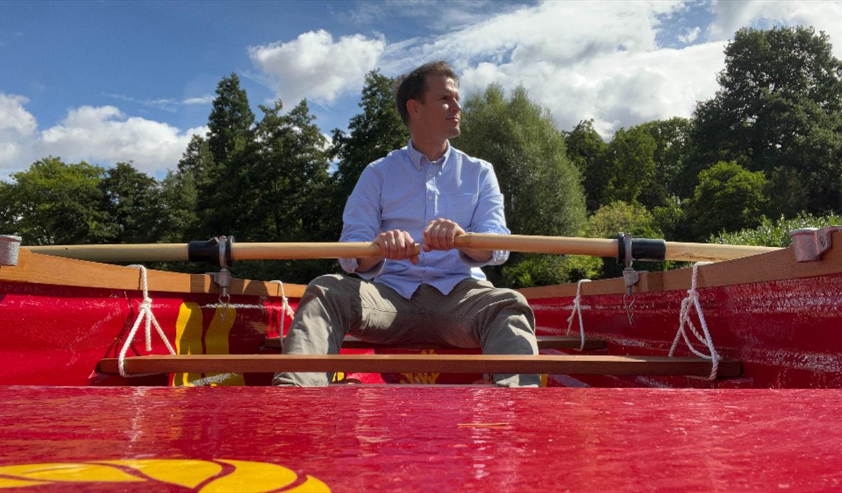 A man rowing a red rowing boat