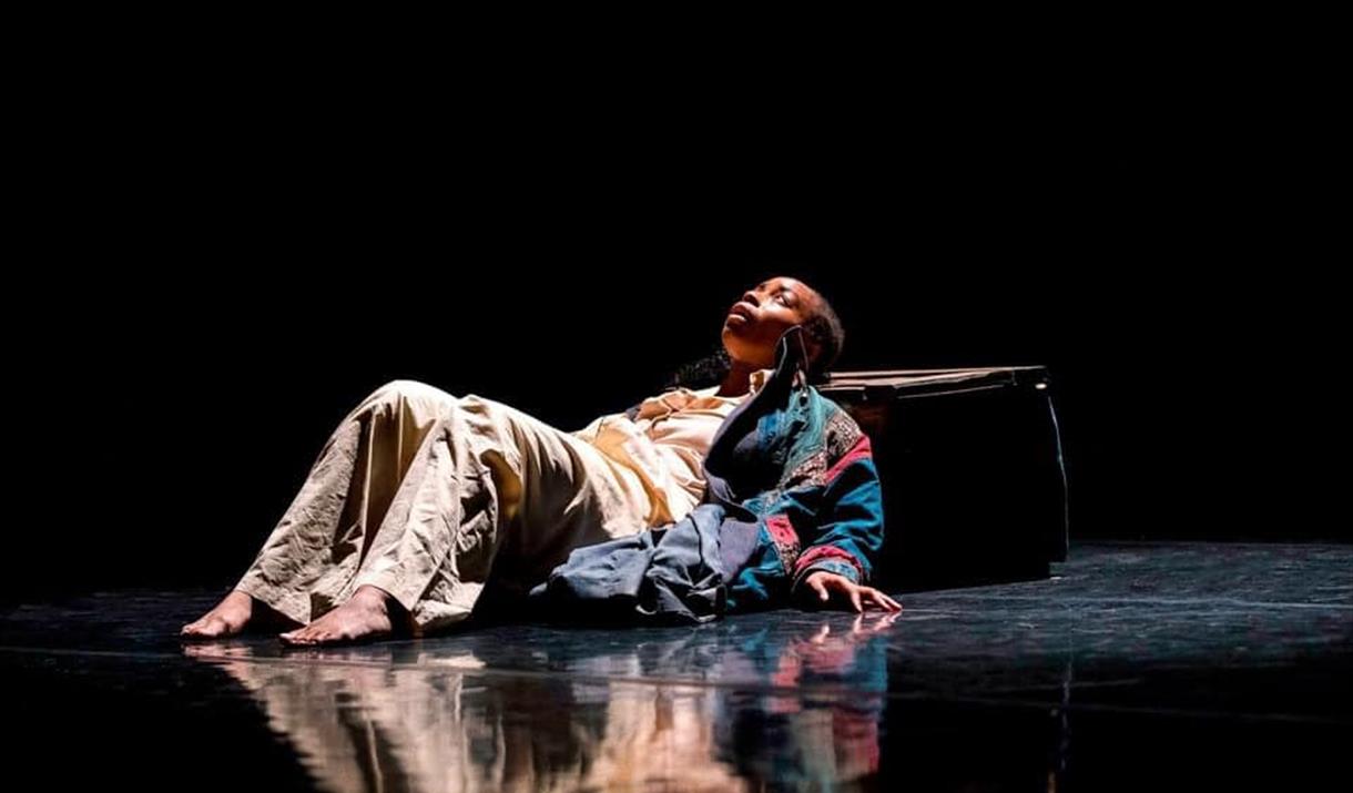 A dance performer lying on the floor looking upwards