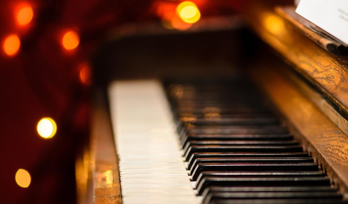 A piano keyboard with a bokeh of Christmas lights in the background