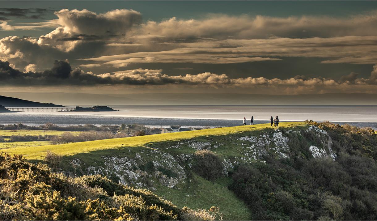 landscape showing cliffs, field, sea under a dramatic sky