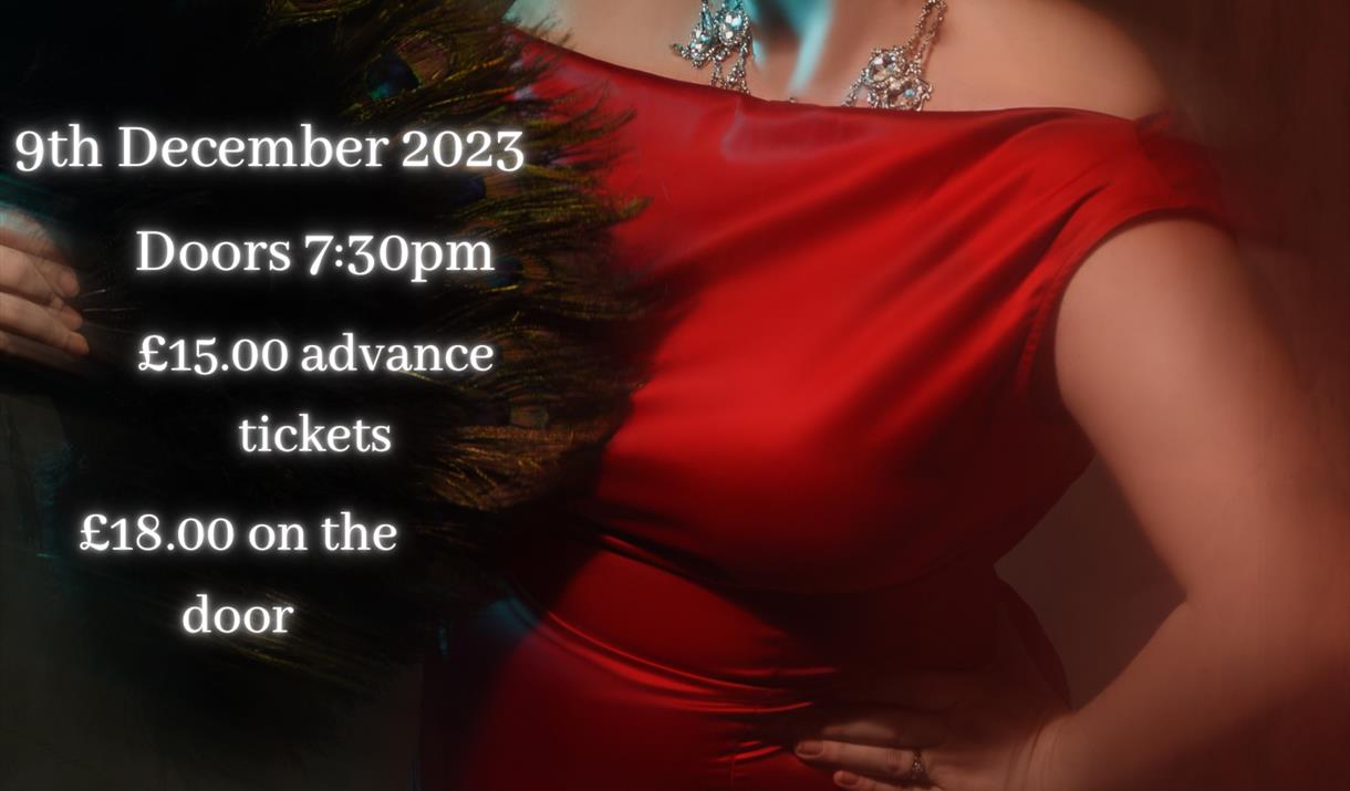 Seren Dippity is in a red dress and big jewellery looking fabulous at the camera, enticing you to come to her show.