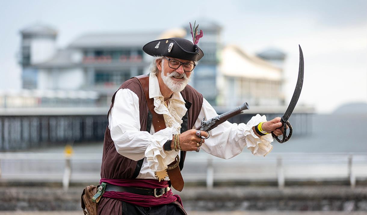 A pirate with a sword and gun outside The Grand Pier at the Weston-super-Mare Sea Shanty Festival