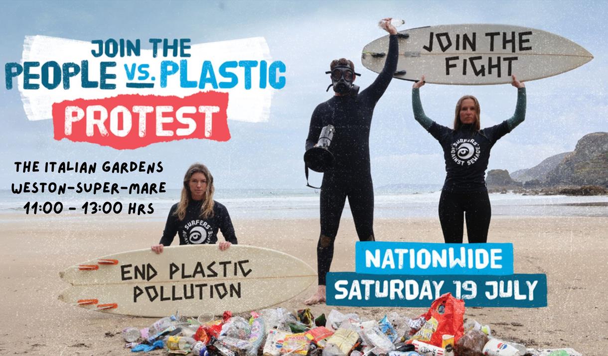 A pile of litter on a beach with three people wearing wetsuits behind it.  The lady on the left kneeling and holding a surfboard in front of her with