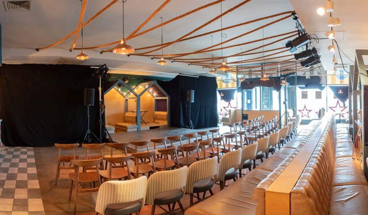 Interior image of a fringe theatre taken from the back looking over seats towards the stage