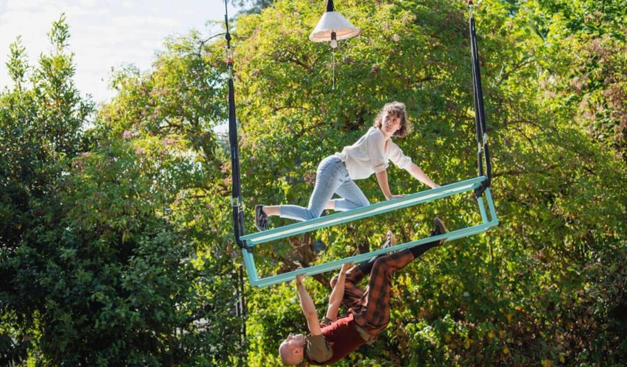 A photo of two people suspended in mid-air from a luggage rack