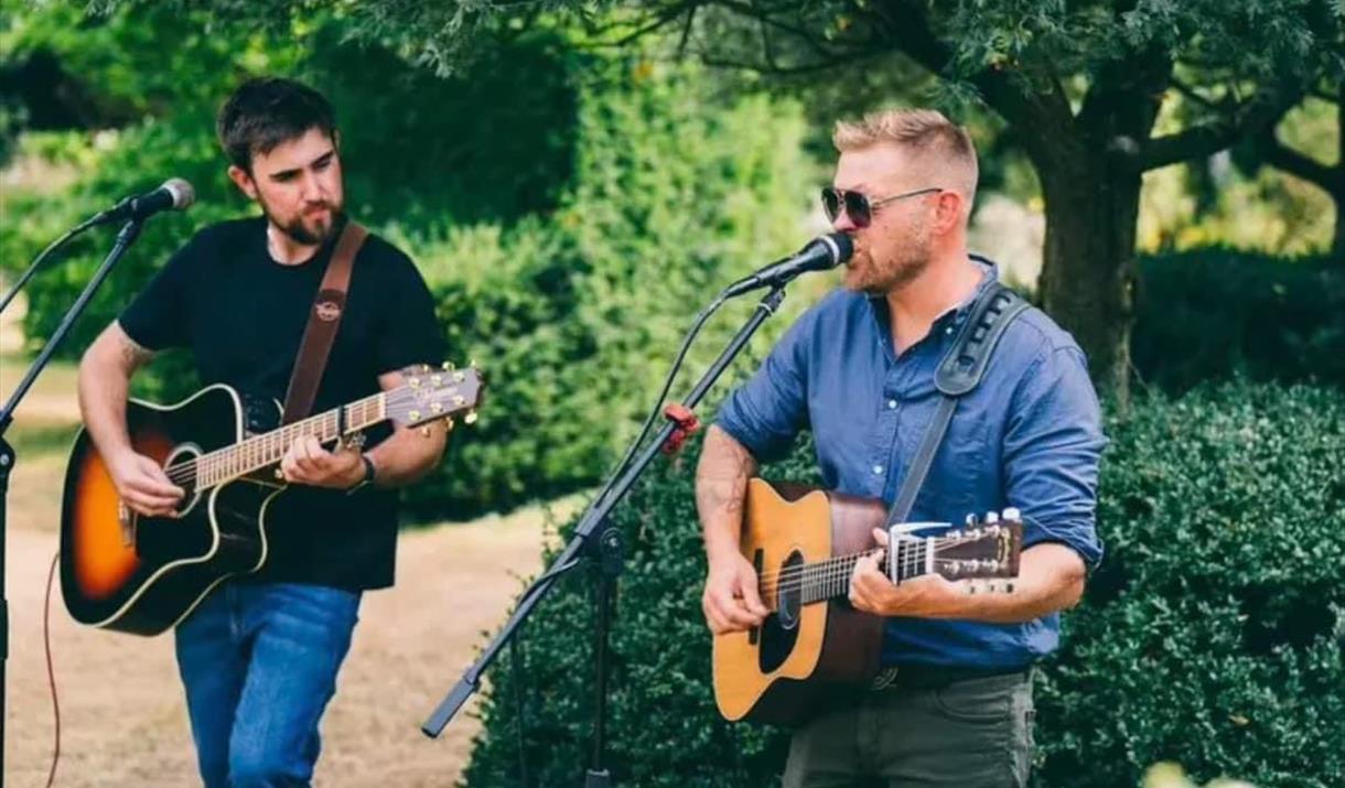 Photograph of the Chicken Teddys playing guitars and singing into microphones.