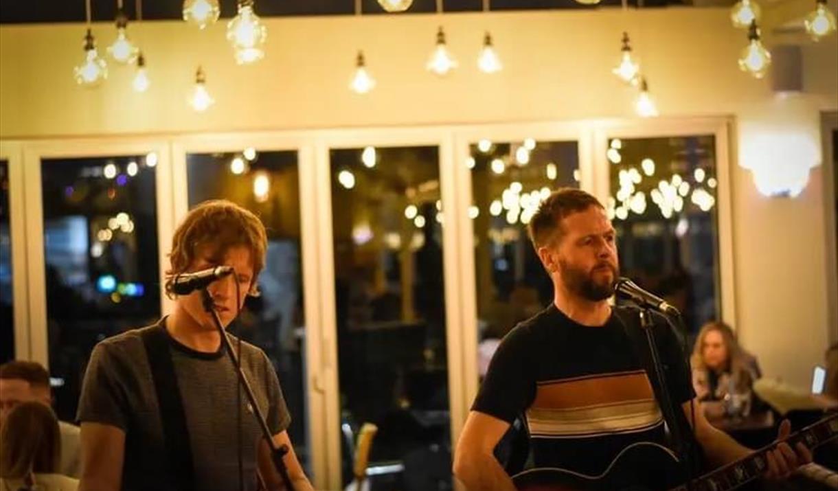 Photograph of Alex and Adam Lipinski singing into microphones at Revo Kitchen