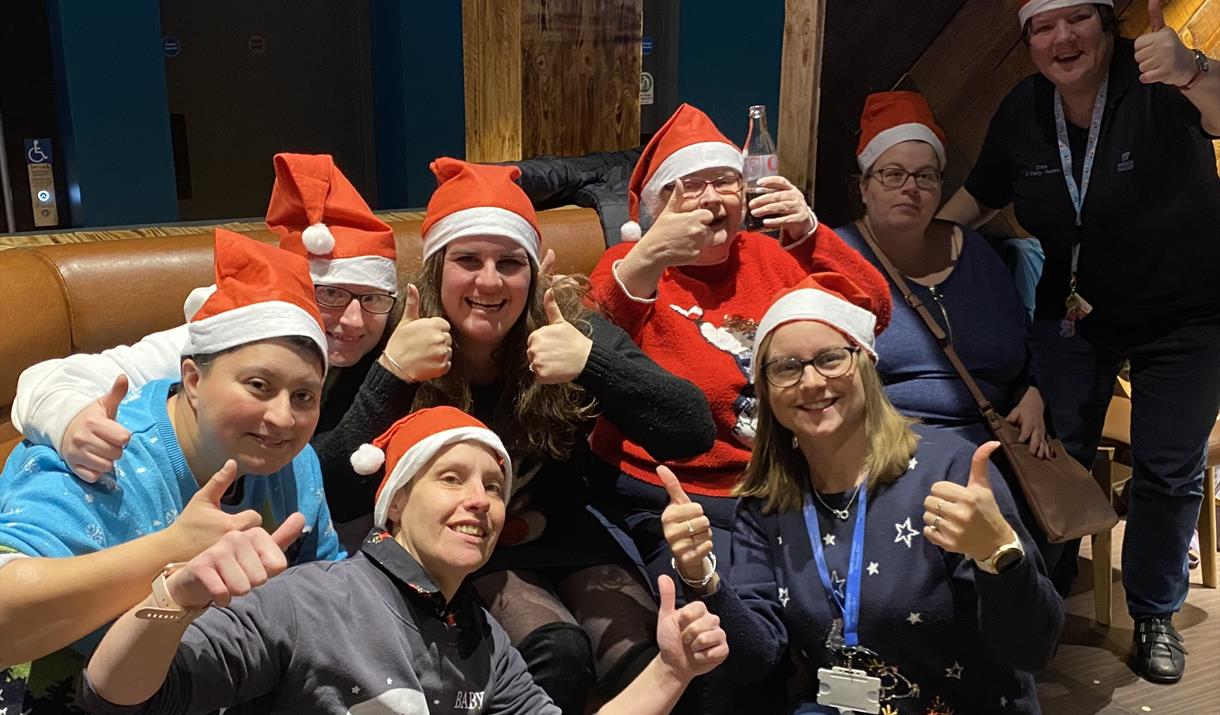 A group of ladies with Learning Disabilities wearing Christmas hats.