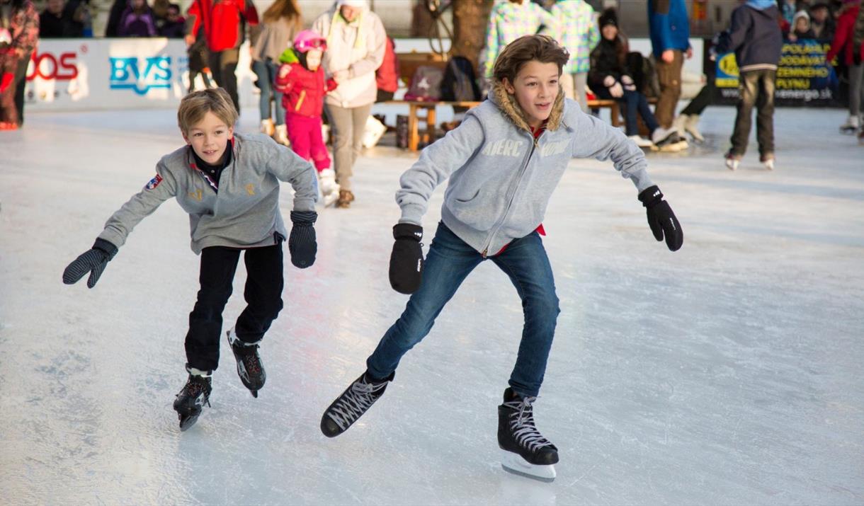 Two boys in grey jackets ice skating