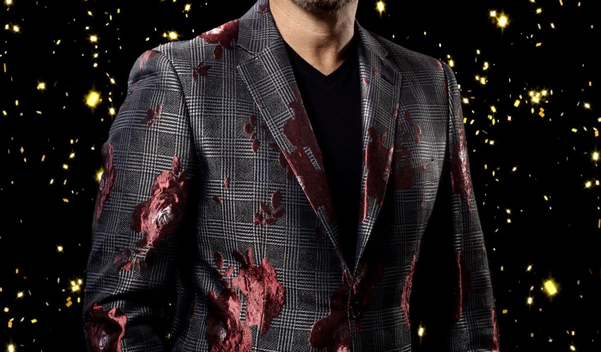 Jon Fisher as Gary Barlow - image of Gary Barlow against a black and gold.
