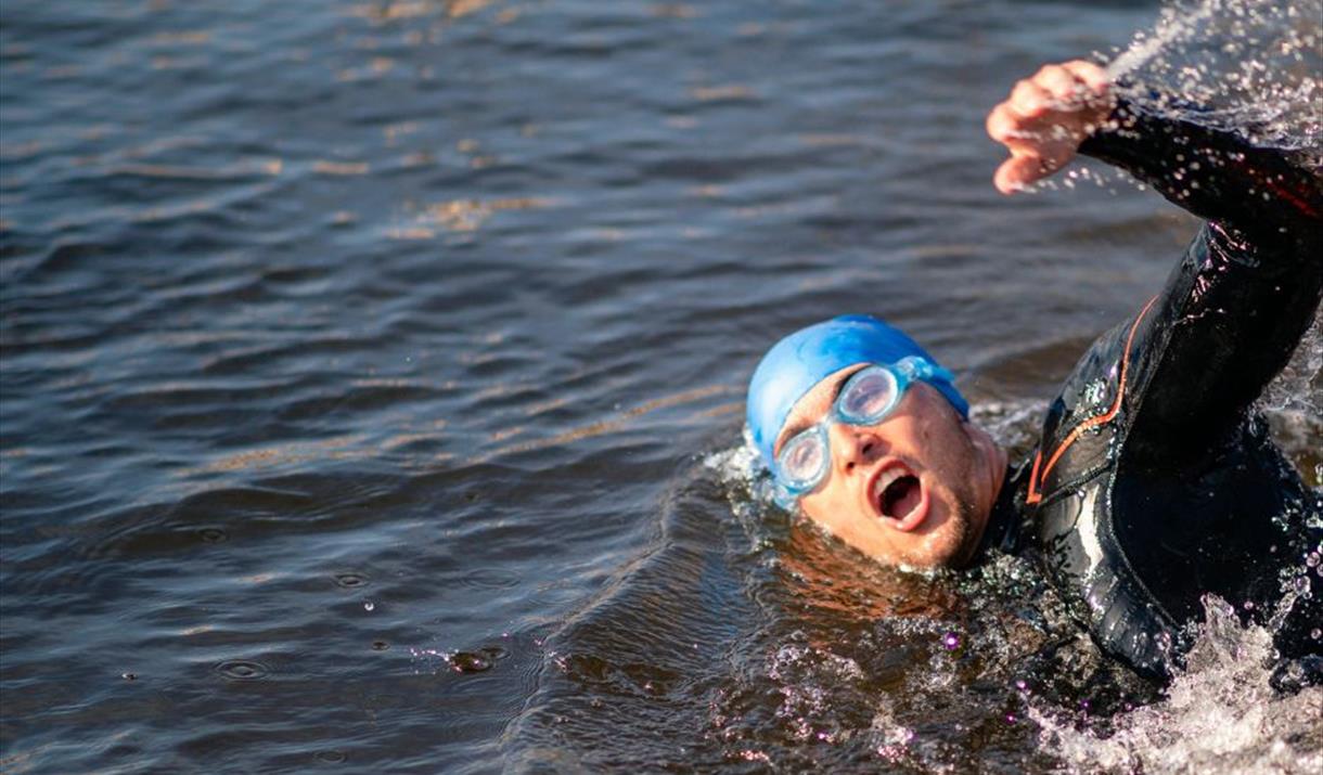 A swimmer in blue swim hat and goggles swimming crawl