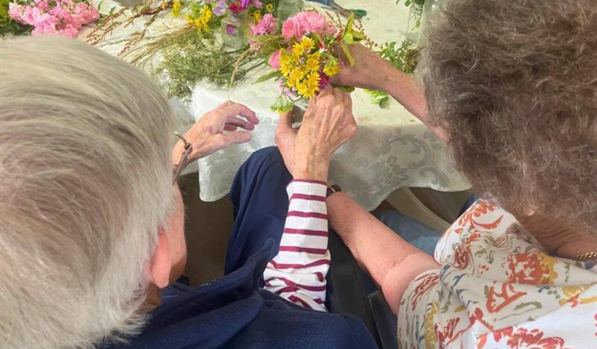 Two people arrange flowers