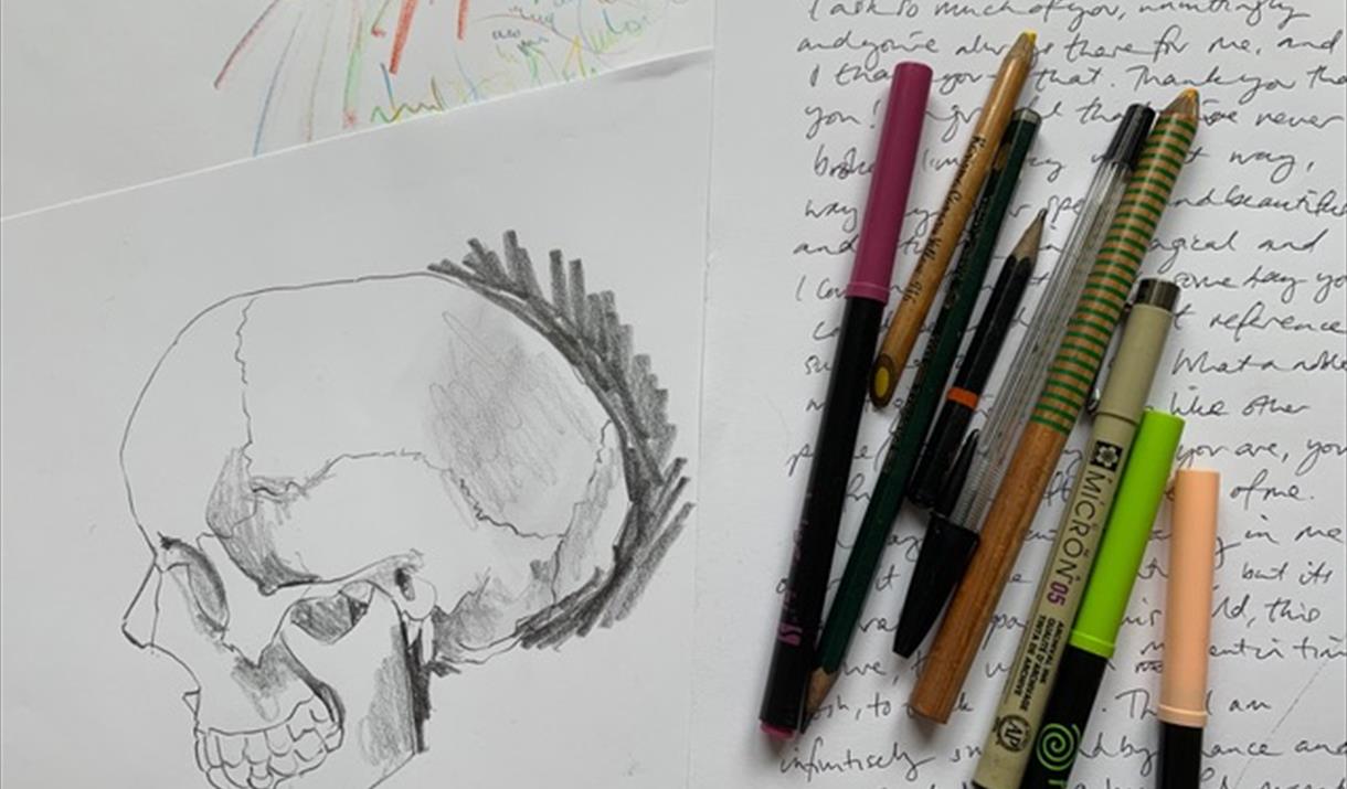 A sketch of a skull, next to some hand-written writing and a selection of stationery