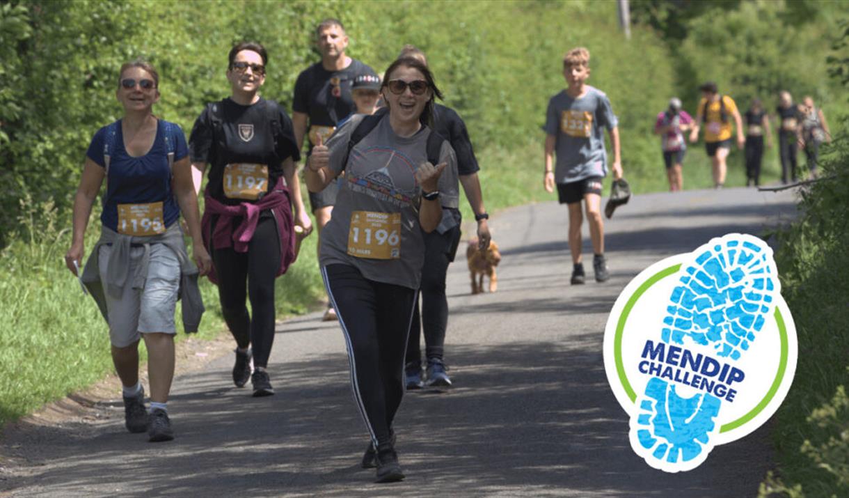 A participant in the Mendip Challenge with her thumbs up with other walkers in the background.