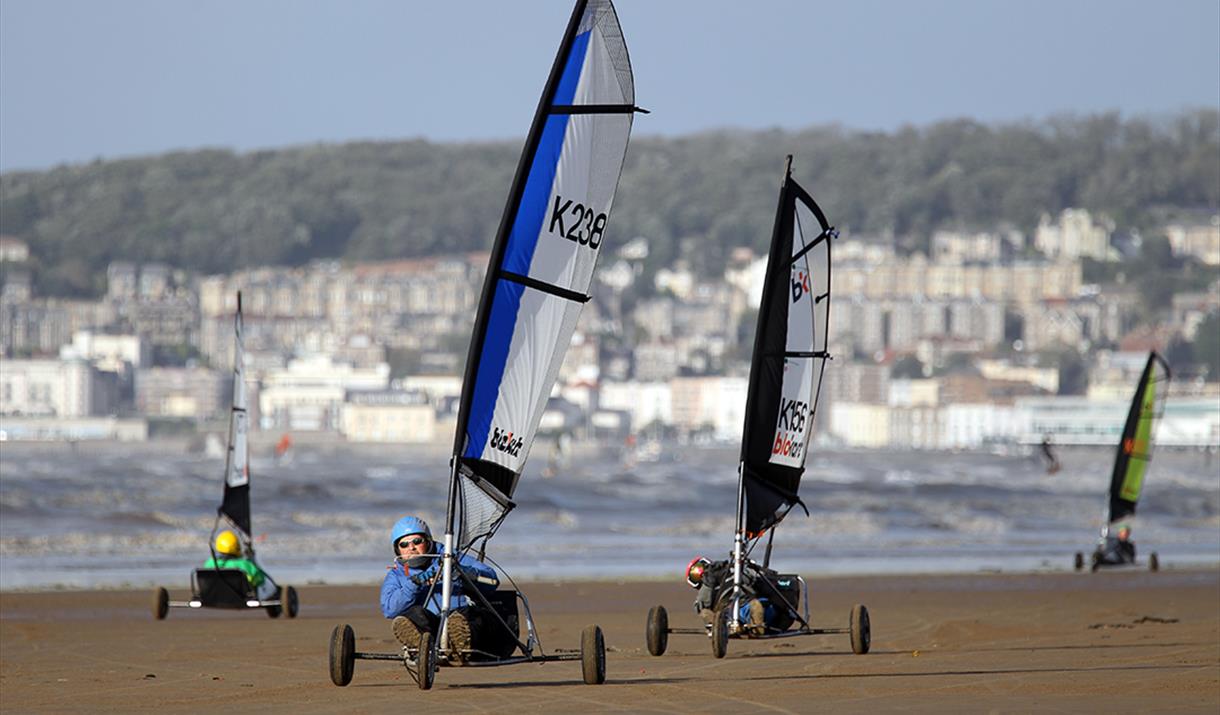 Four Blo-karts or land yachts racing along a sandy beach