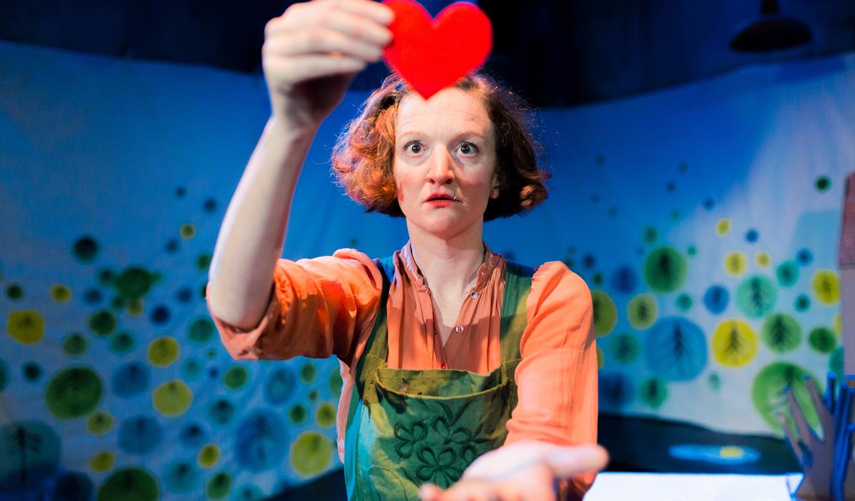 Bright photograph of an actor holding a felt red heart.