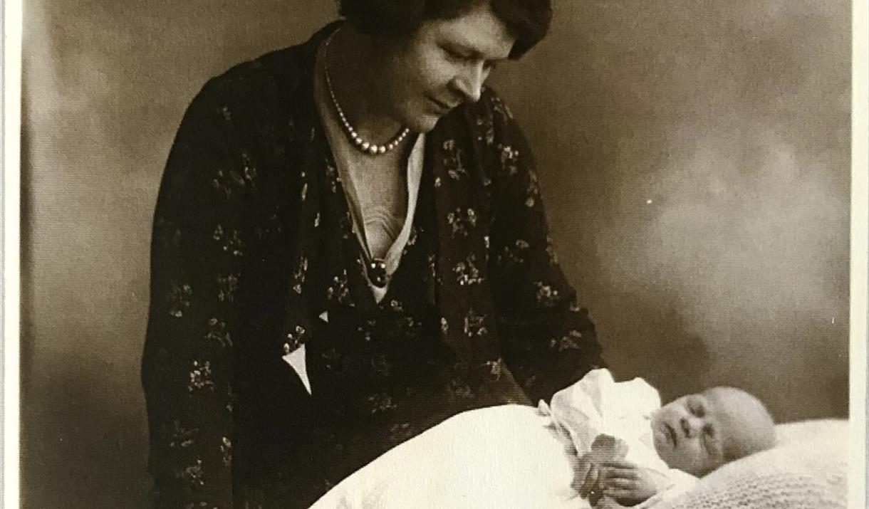 A sepia-toned photograph of a woman looking down at a baby