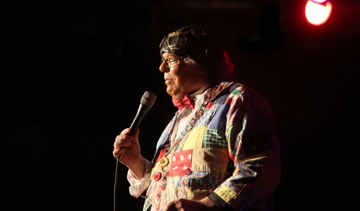 Roy Brown on stage holding a microphone with a spot light on him.