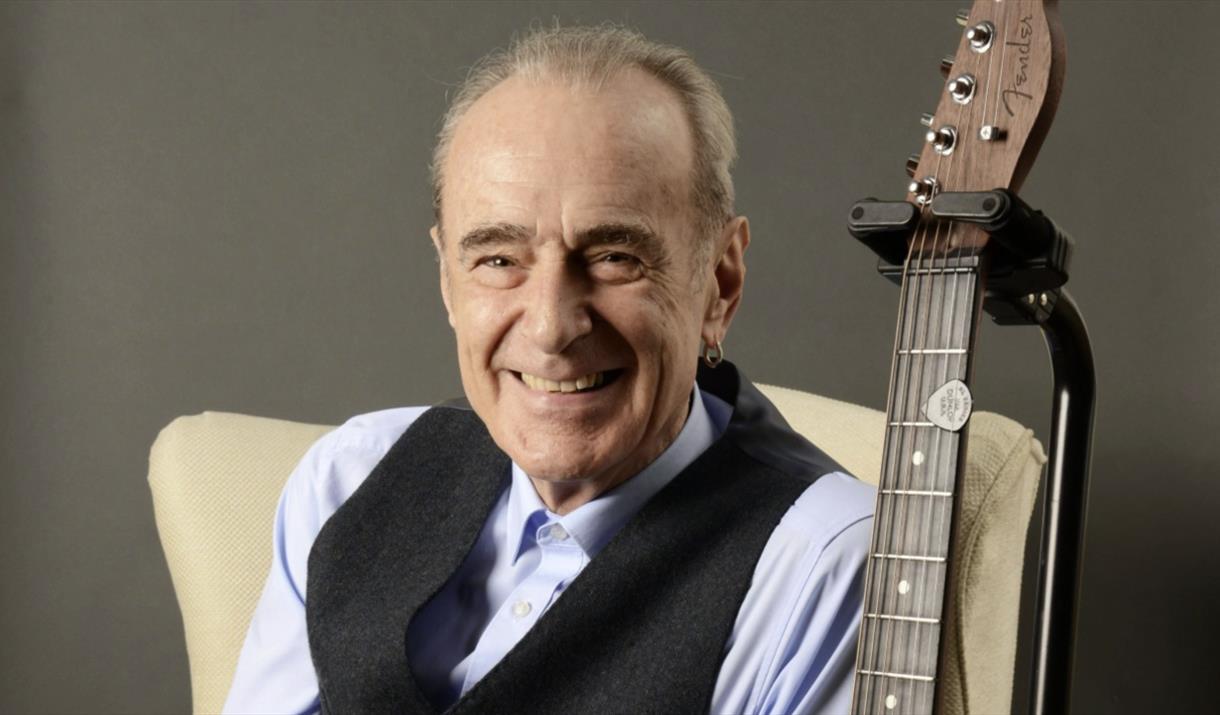 Francis Rossi sitting next to a guitar.