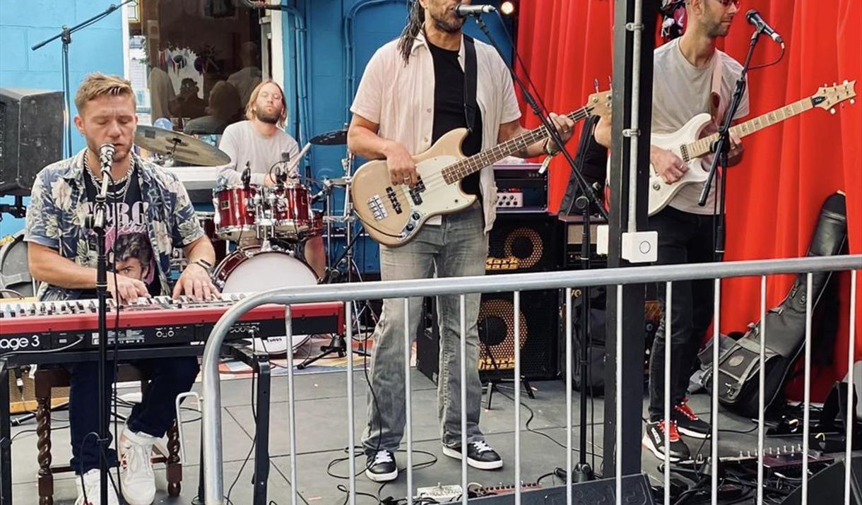 A band of four men  performing behind a fence