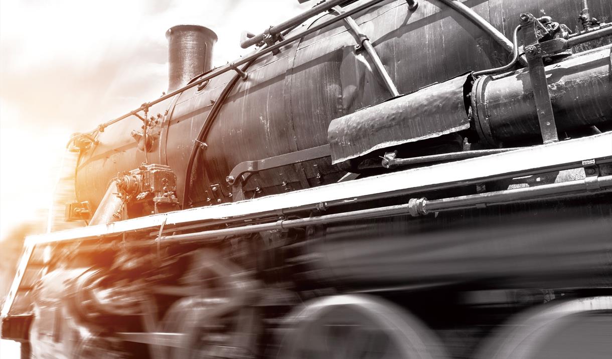 A blurred black, white and sepia image of the front of a steam train travelling at speed