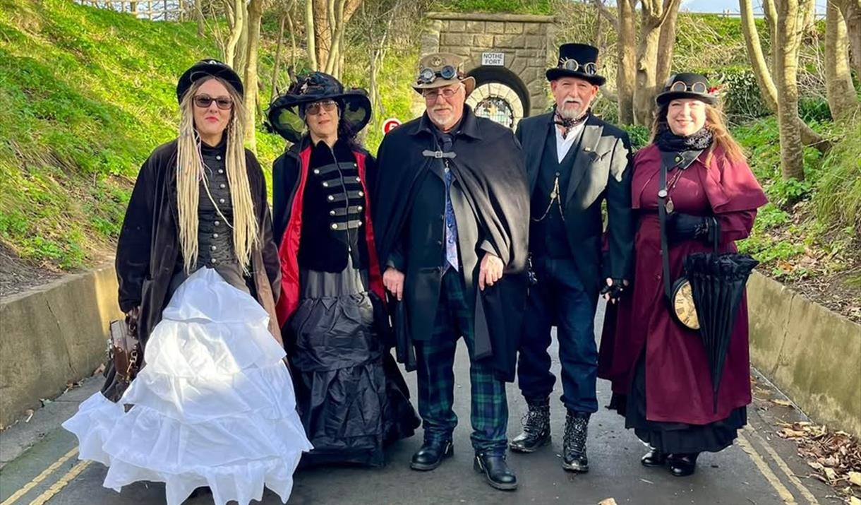 Five Steampunks dressed in traditional costume on a countryside road