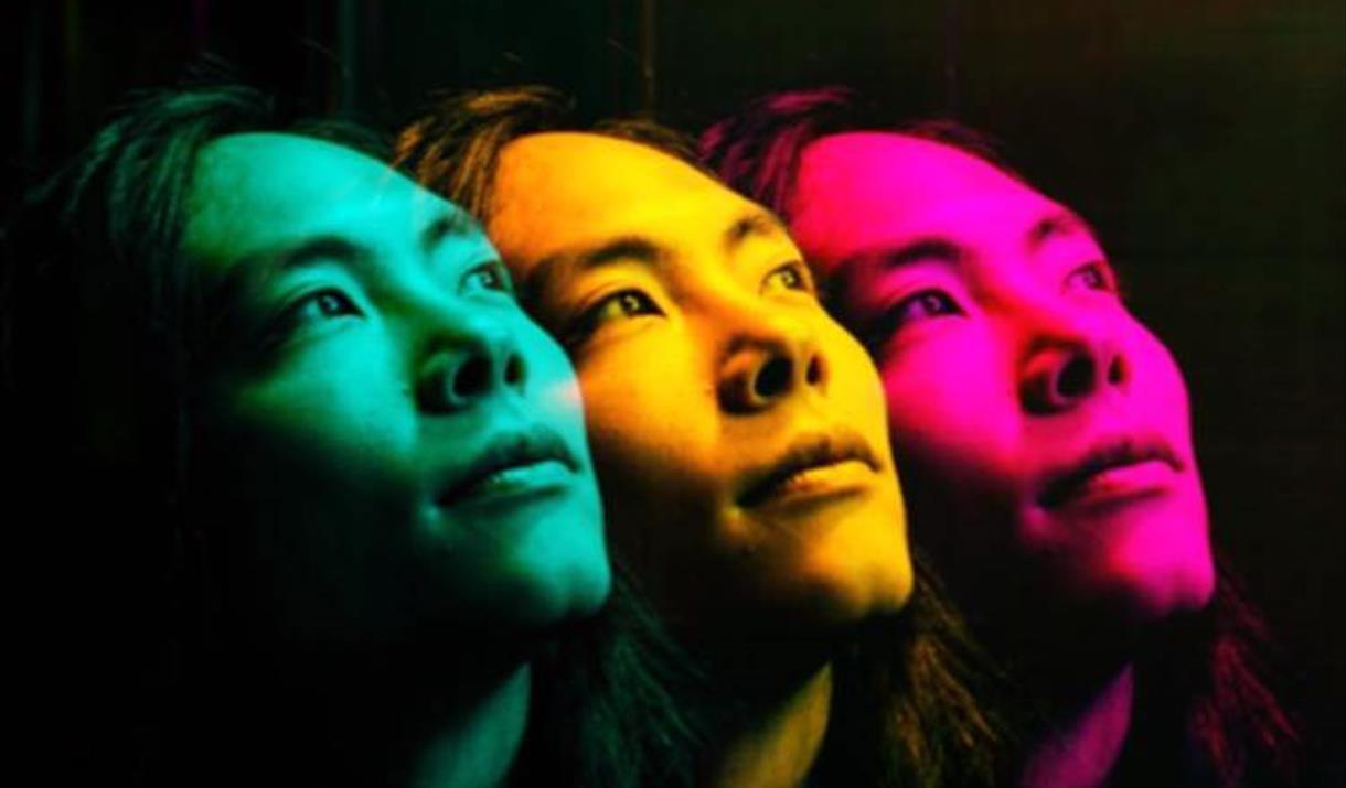 Theo Mizu in profile green, yellow and pink face on a black background