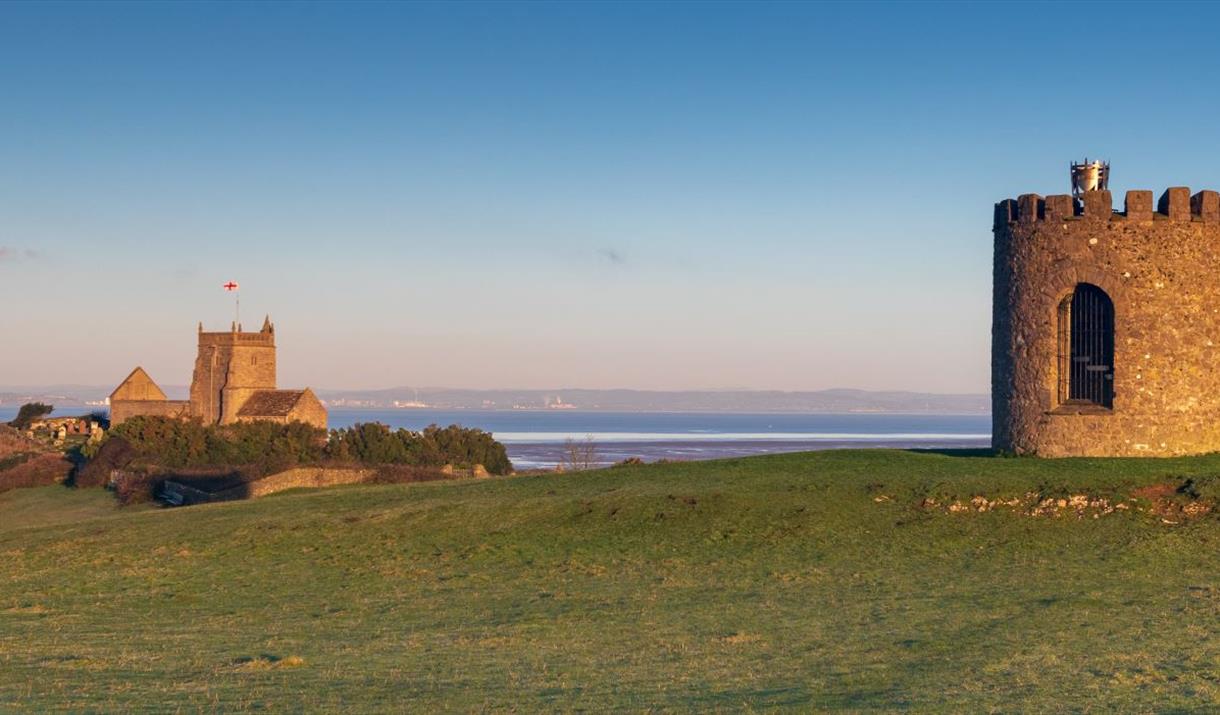 A beacon and a church separated by a green field