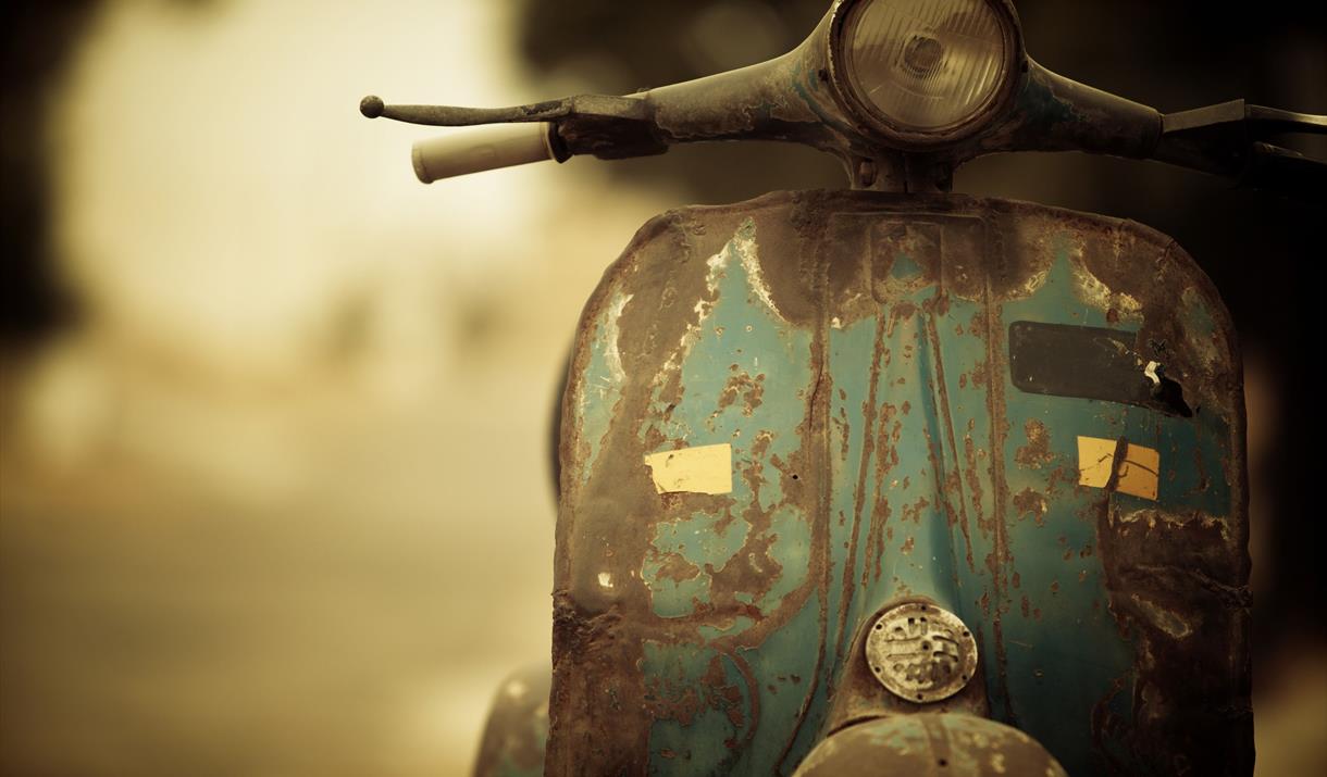 Front view of a rusty green Vespa-style scooter