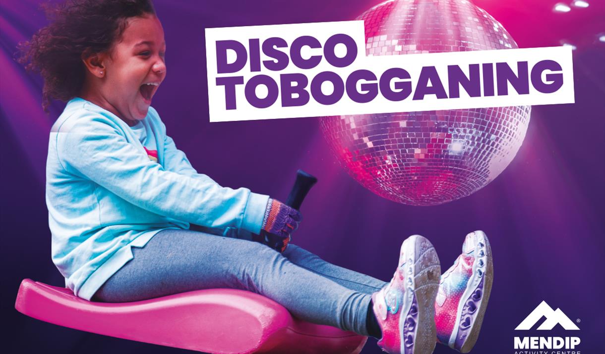 Little girl looking happy and excited riding a zibob toboggan. Background display a disco ball on a purple background, with light glowing down onto th