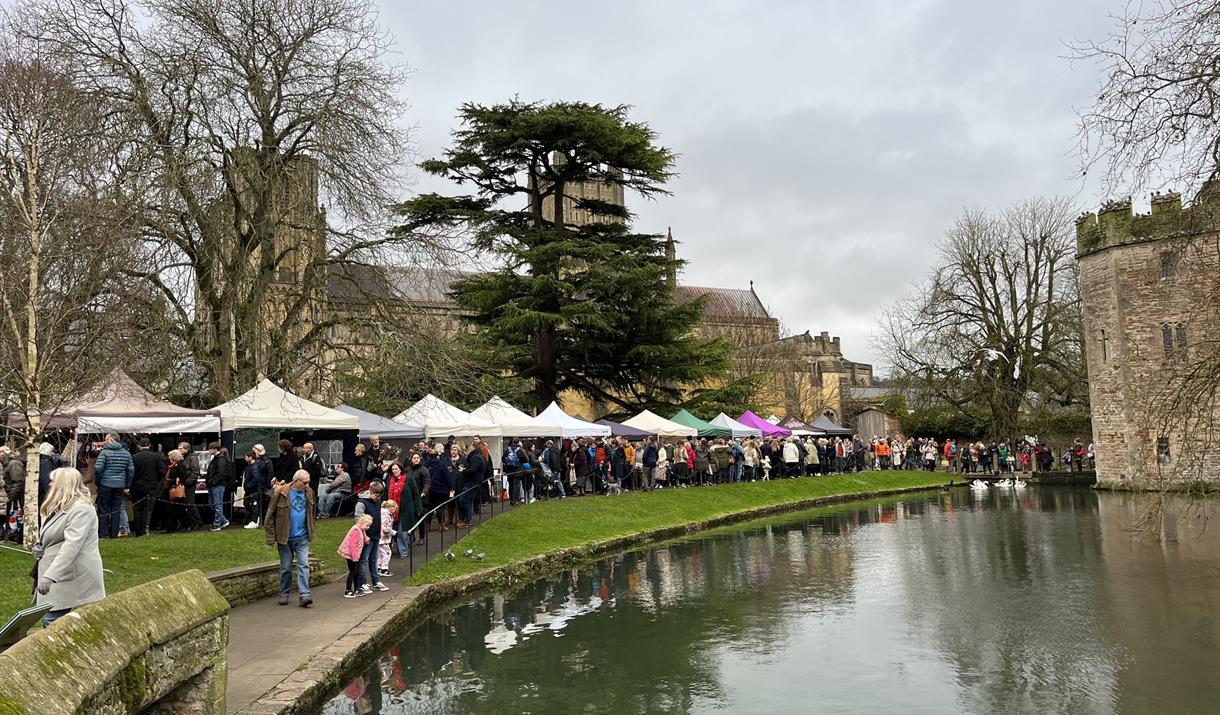 Christmas market stalls line the pretty banks of the river that forms a moat around the Bishop's Palace in Wells